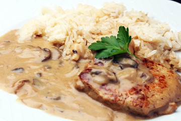 Delicious rice with chicken and vegetables on plate on wooden table