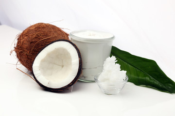 Coconut with leaves and coconut oil in jar on wooden background
