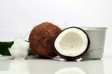 Coconut with leaves and coconut oil in jar on wooden background