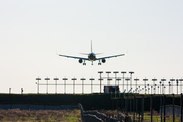 Silhouette of passenger aircraft on landing with approaching runway lights