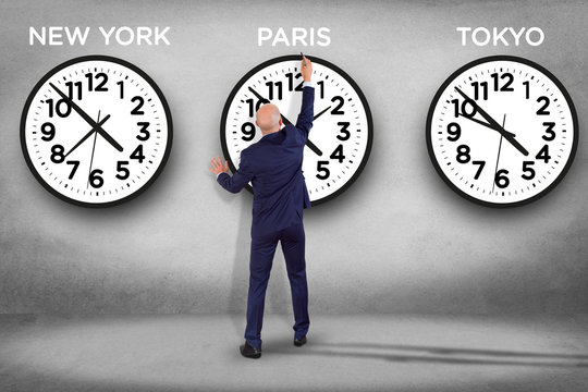 Businessman in front of a wallwith clocks of different country - Jetlag concept