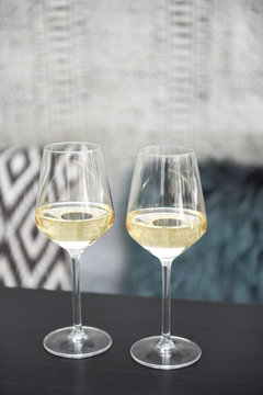 Aperitif with two glasses of white wine on a terrace with black and white bench and green cushion with geometric motifs