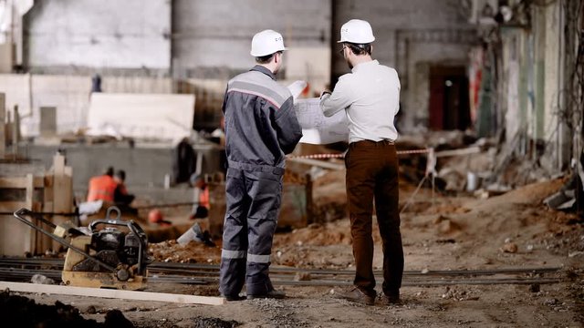 Construction of an industrial facility. The master speaks with the chief engineer of the project. Mens communicate.