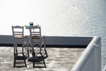 Terrace with two chairs, table and amazing view on Aegean sea, Santorini, Greece