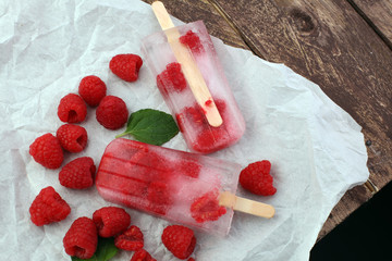 Healthy raspberry popsicles with fresh slices on wooden background