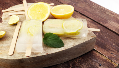 Healthy lemon popsicles with fresh lime slices on wooden background