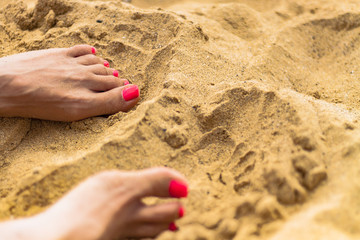Women foot on beach sand with red