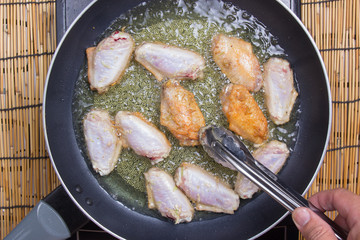 Chef frying chicken wings in pan