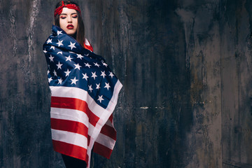 Girl wrapped in american flag on dark background. Patriot, national event celebration, pride, usa citizen concept