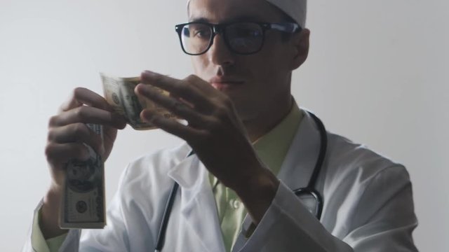 The doctor kisses a 100 dollar bill. A bribe to a medical worker. Expensive medicine.
