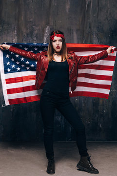 Fashion girl with USA flag behind the back on dark background. American patriot, national event celebration, pride, usa citizen concept
