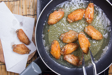 Chef frying chicken wings in pan