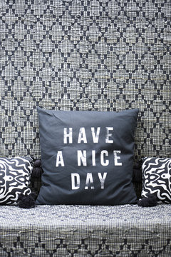 Sofa covered with an ethnic patterned fabric and black and white cushions "have a nice day"