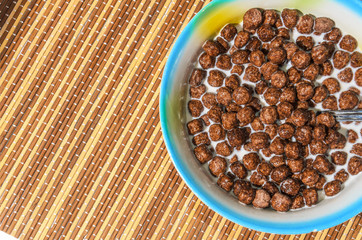 Flakes of cereals in a blue plate on a bamboo napkin