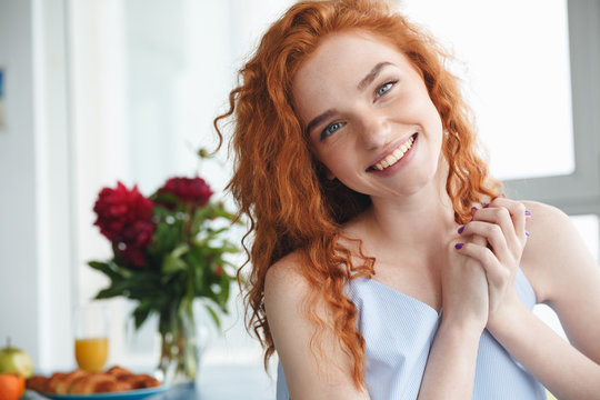 Cheerful young redhead lady sitting near flowers