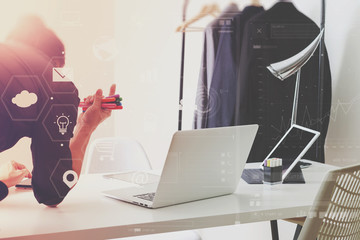 Fashion designer working with mobile phone and using laptop with digital tablet computer in modern studio