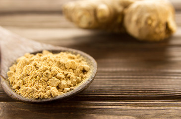 Ginger powder in wooden spoon on wooden table.