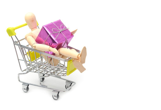 Wooden dummy holding gift box in shopping cart, shopping concept