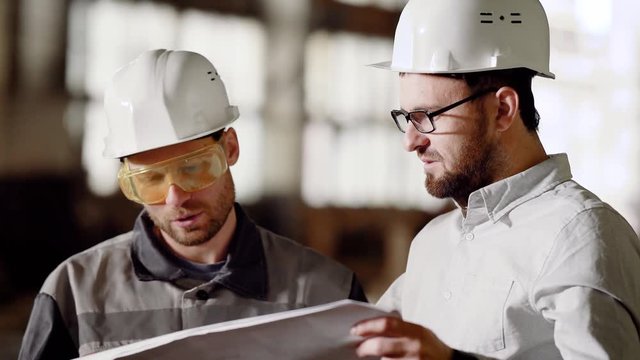 Chief engineer and master of construction at an industrial facility. The engineer looks at the plan and discusses it with the chief foreman at the construction site.