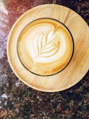Latte art in cup on wood and marble with sunset background.
