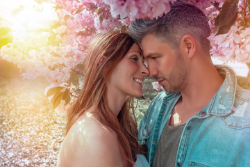 young couple kissing under blooming tree