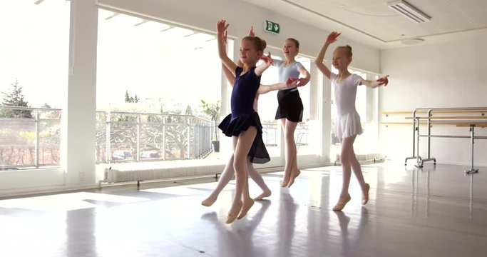 Group of small sporty pretty girls exercising and dancing ballet in the class.