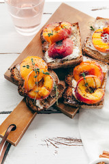 Summer snack: sandwiches with grilled peaches, cream cheese, thyme and pecan with a glass of chilled rose wine on distressed white wooden background