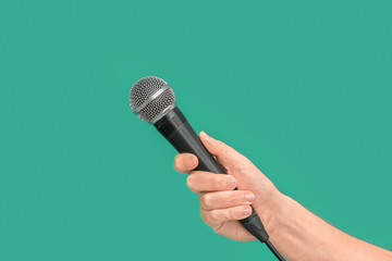 Interviewer or reporter with microphone in hand on green background
