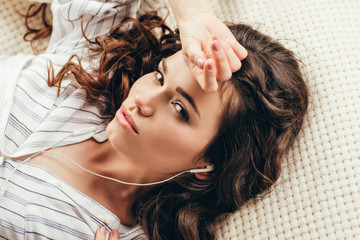 Close-up portrait of beautiful brunette young woman wearing earphones and looking at camera