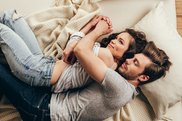 Top view of beautiful happy young couple hugging while sleeping on bed