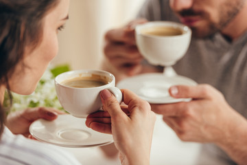 cropped shot of young couple drinking coffee at home