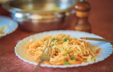 Spaghetti carbonara, italian pasta, on a white plate with a fork and knife
