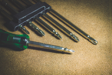 Close-up of screwdriver and small screw on tip set head screw driver and screw on wood background