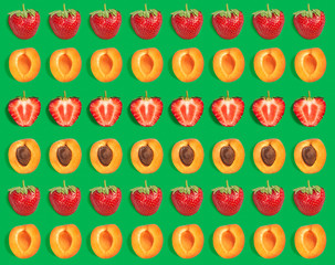 Colorful fruit pattern of fresh apricot and strawberry slices on green background. From top view