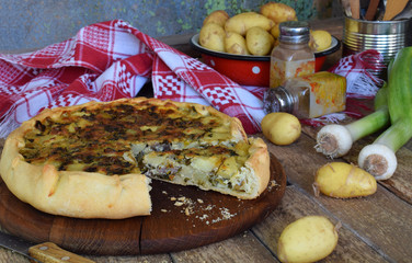 Savory pie with potatoes, meat, cheese, onion and pepper. Leek quiche for dinner or lanch on wooden background. Copy space for your text.