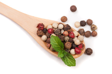 Mixture of peppers hot, red, black, white and green pepper in a wooden spoon isolated on white background. Top view