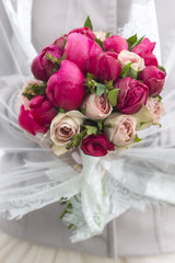 vivid and bright bouquet of different flowers . he holds the bride in a veil.