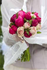 vivid and bright bouquet of different flowers . he holds the bride in a veil.