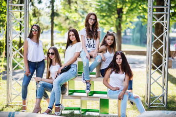Six wonderful model girls posing on wooden boxes in the park on a sunny day.
