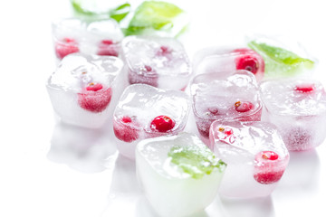 Ice cubes with berries and mint for summer drink on white background
