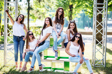 Six wonderful model girls posing on wooden boxes in the park on a sunny day.