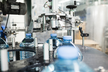 Industrial factory indoors and machinery. Robotic factory line for processing and bottling of pure spring water into canisters and bottles. Selective focus. Short depth of field.