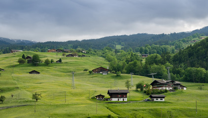 Fototapeta premium Pastoral view on typical swiss houses on green hill at Grindelwald village. Interlaken-Oberhasli district. Switzerland