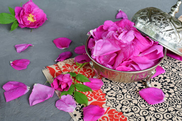 Obraz na płótnie Canvas tea-rose petals in metal sugar bowl: for tea, alternative medicine, pot-pourri. Copy space for text.