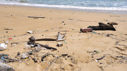 Pollution on the beach of tropical sea. Plastic garbage, foam, wood and dirty waste on beach in summer day.