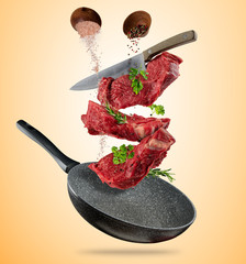 Flying raw steaks with cooking ingredients from pan