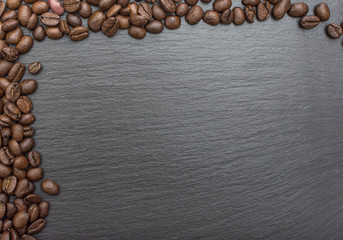 Red rice and olive wood scoop on black background of slate or stone. 