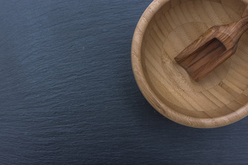 Red rice and olive wood scoop on black background of slate or stone. 