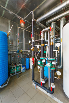 The interior of a modern gas boiler house with pumps, valves, a multitude of sensors and barrels