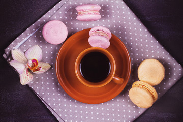 Obraz na płótnie Canvas Coffee, orchids and cake macaron or macaroon on gray background from above. Flower, drink and coockie still life. Flat lay, top view. Soft pink toning